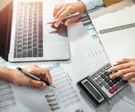 Accountant using calculator and meeting with colleague 