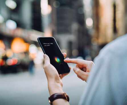 Over the shoulder view of young businesswoman using AI assistant on smartphone