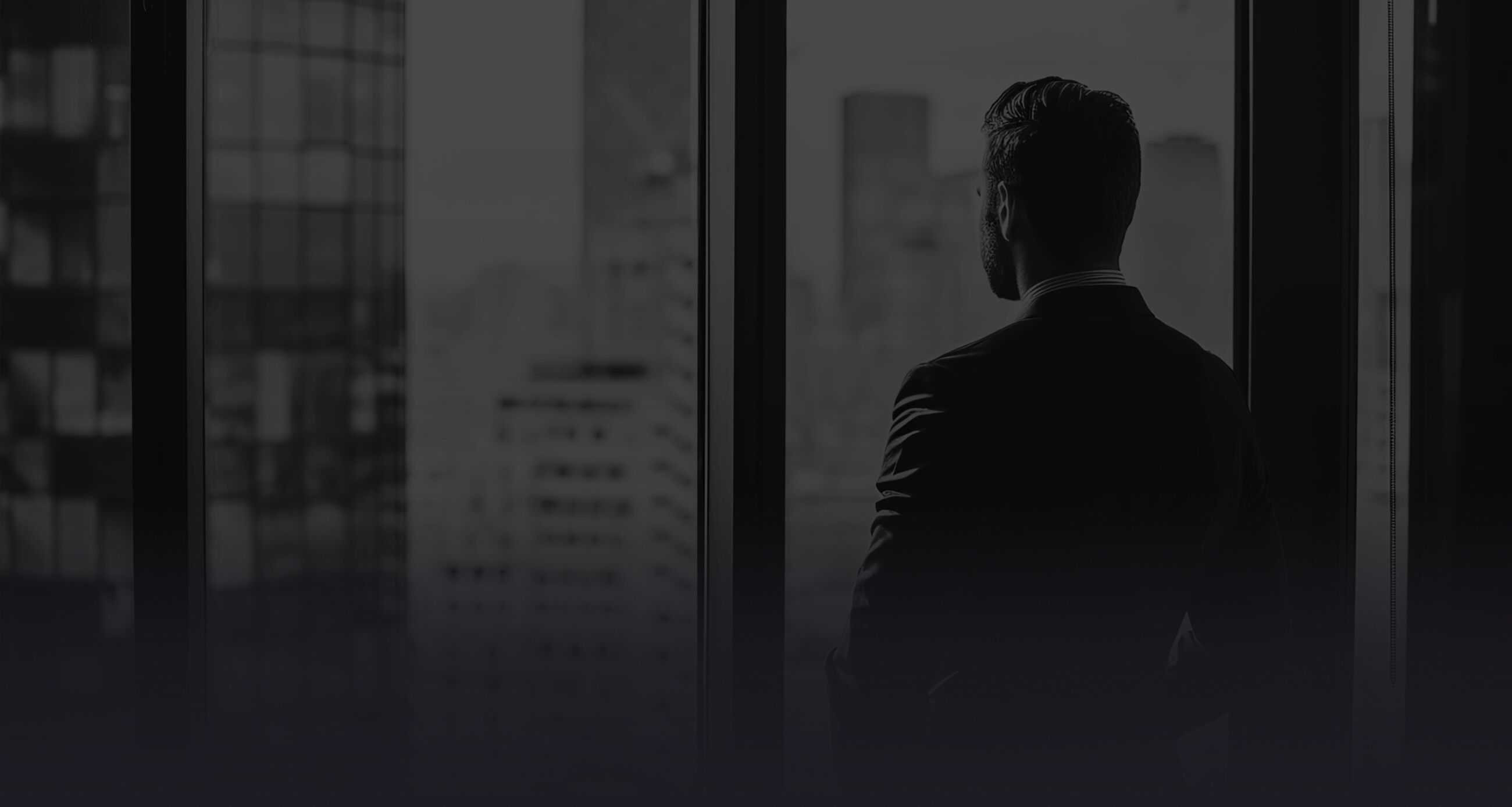Business man in suit in office looking at modern city with skyscrapers through panoramic window