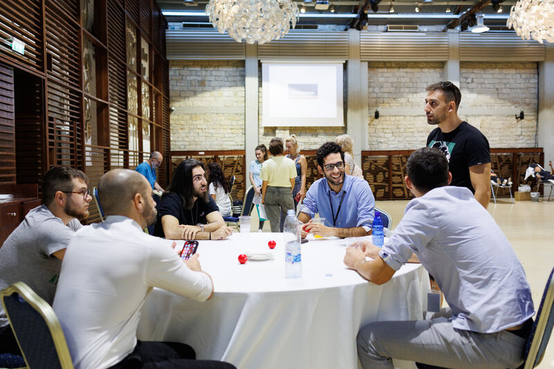 A group of people sitting around a round table chatting